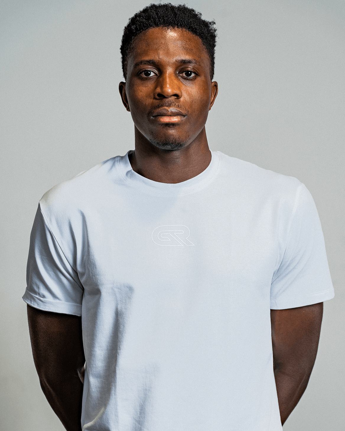 Man wearing a plain white t-shirt against a gray background
